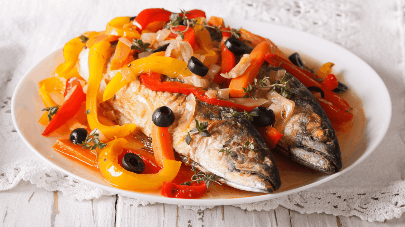 Fisch angerichtet auf einem Teller mit Paprika und Oliven